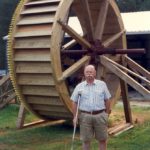 Jeff Suggs standing beside the waterwheel he built for Yates Mill.